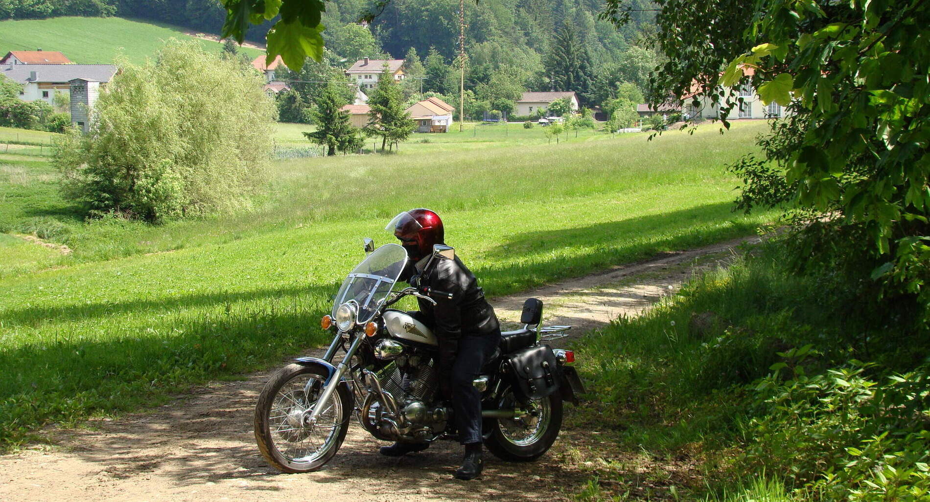 Ein Motorradfahrer macht eine Pause auf einem Feldweg im Bayerischen Wald.